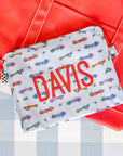 Fabric pouch with 'DAVIS' printed on it and car pattern, against a red and gray background.