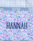 Two pouches with embroidered names on a blue checkered background