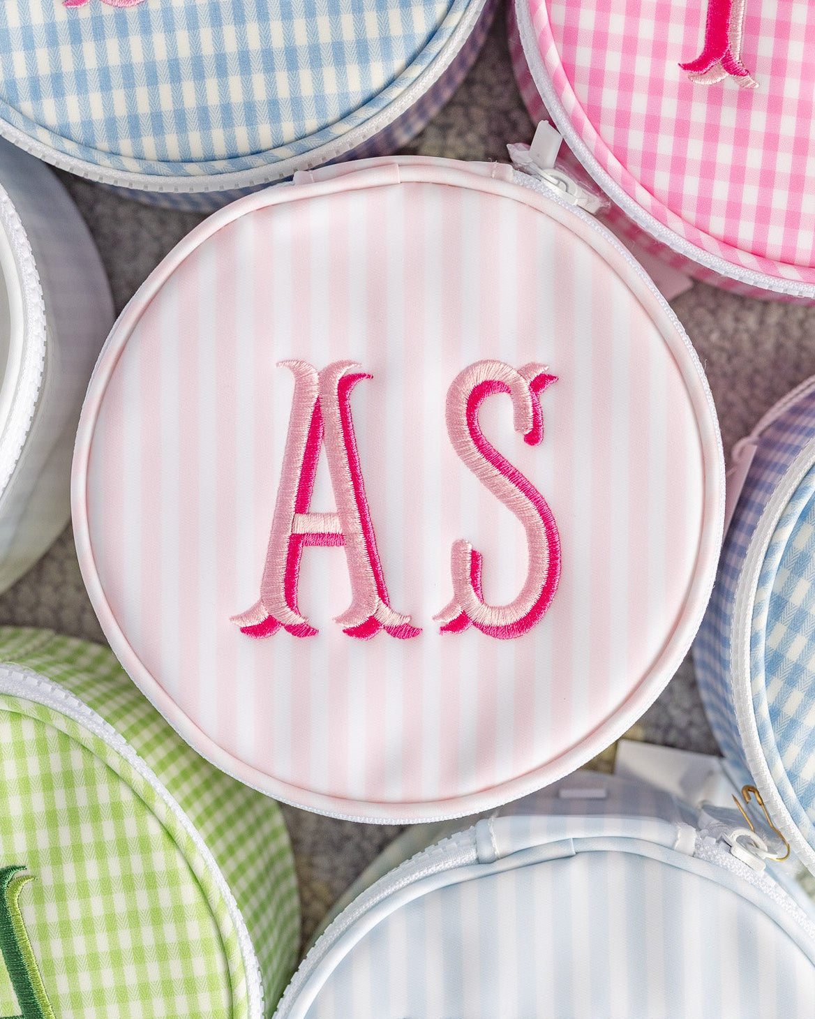 Round pouches with embroidered initials on a checkered background