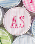 Round pouches with embroidered initials on a checkered background