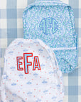 Two backpacks with monogrammed initials on a patterned background