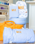 Blue and white striped bags with 'MAX' embroidery, one on a chair, another on the floor, with an orange bag in the foreground.