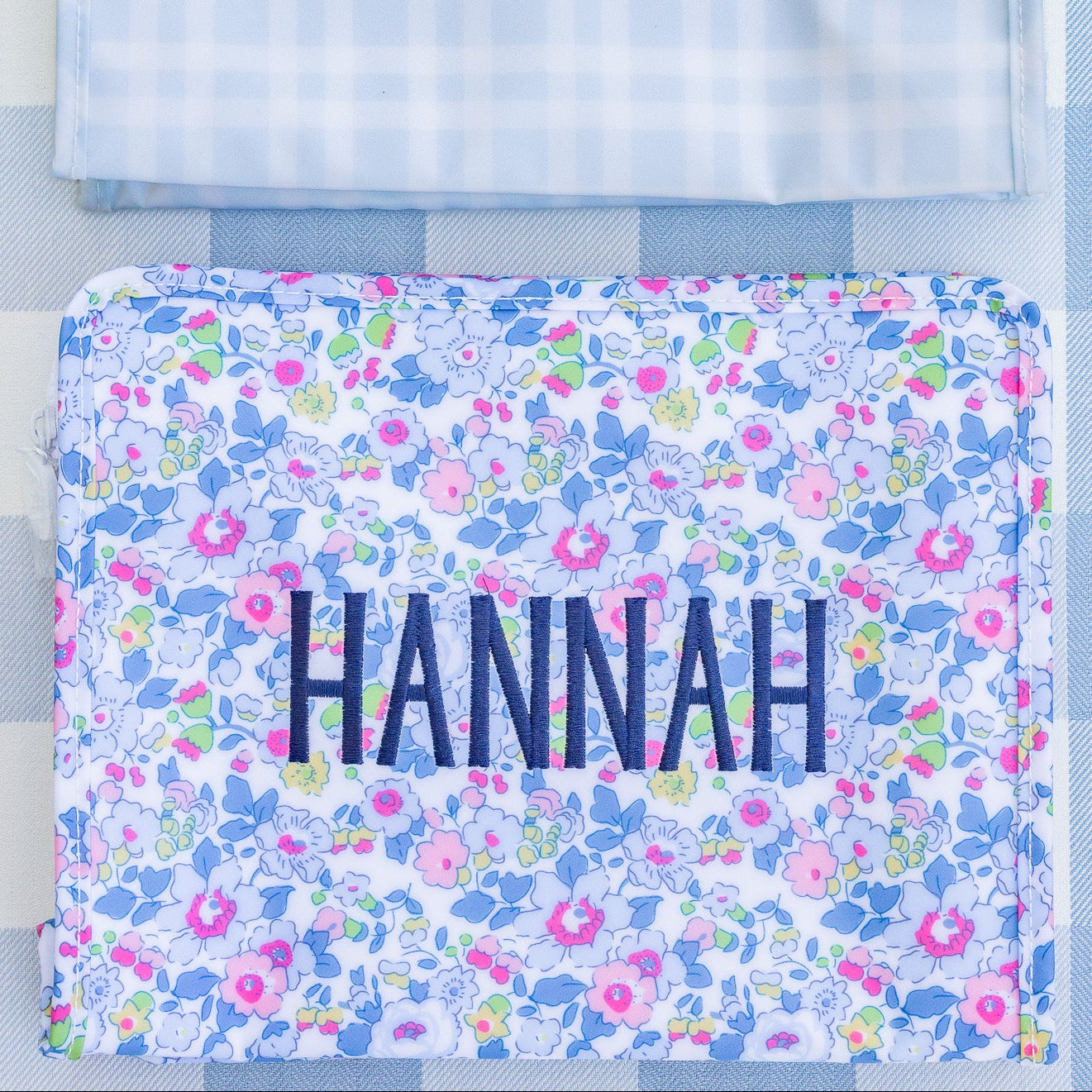 Two pouches with embroidered names on a blue checkered background
